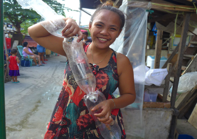 girl smiling in the camera holding recyclable plastic bottles