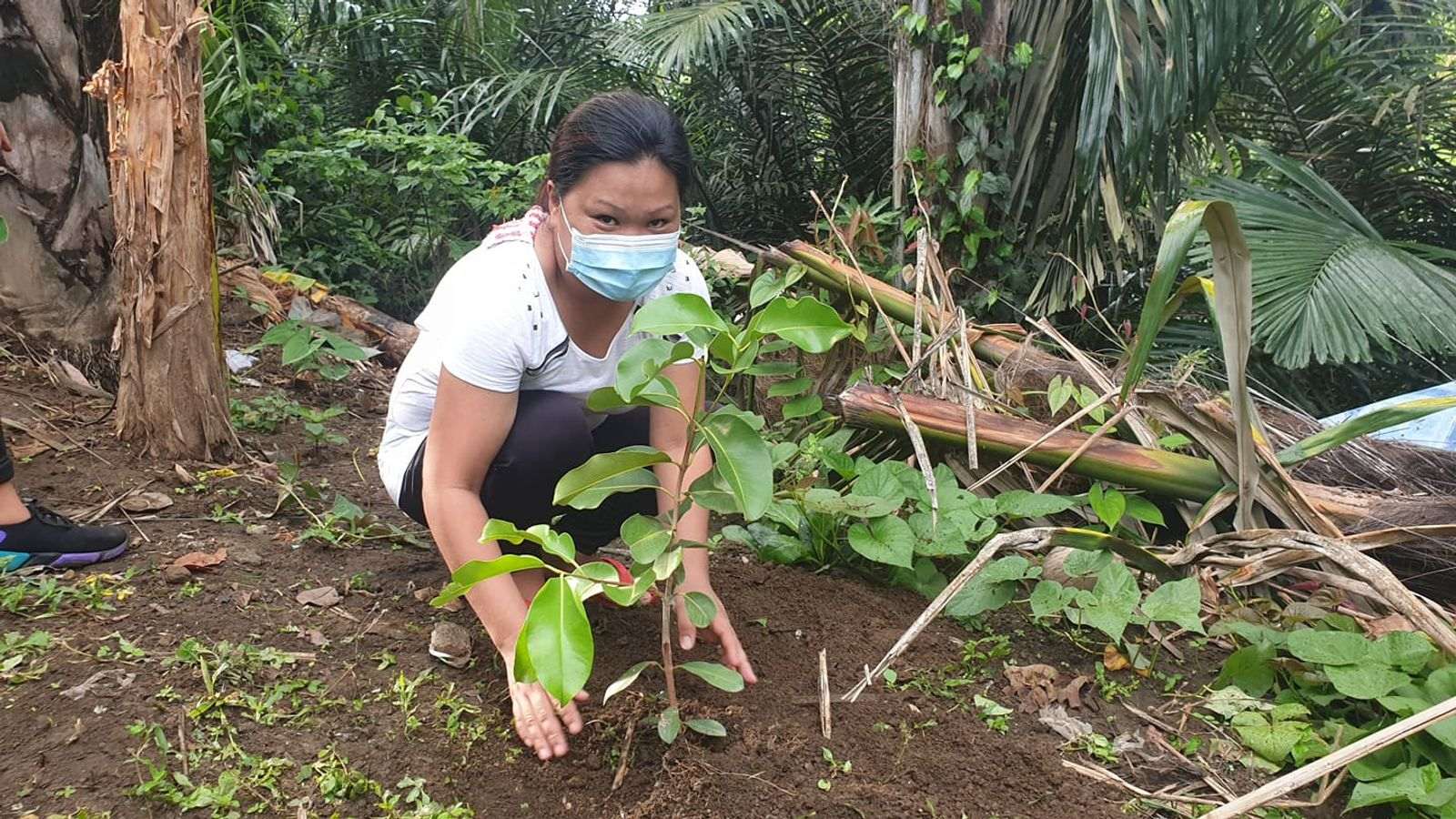 A resident of Brgy. Pansol posing behind the newly planted tree