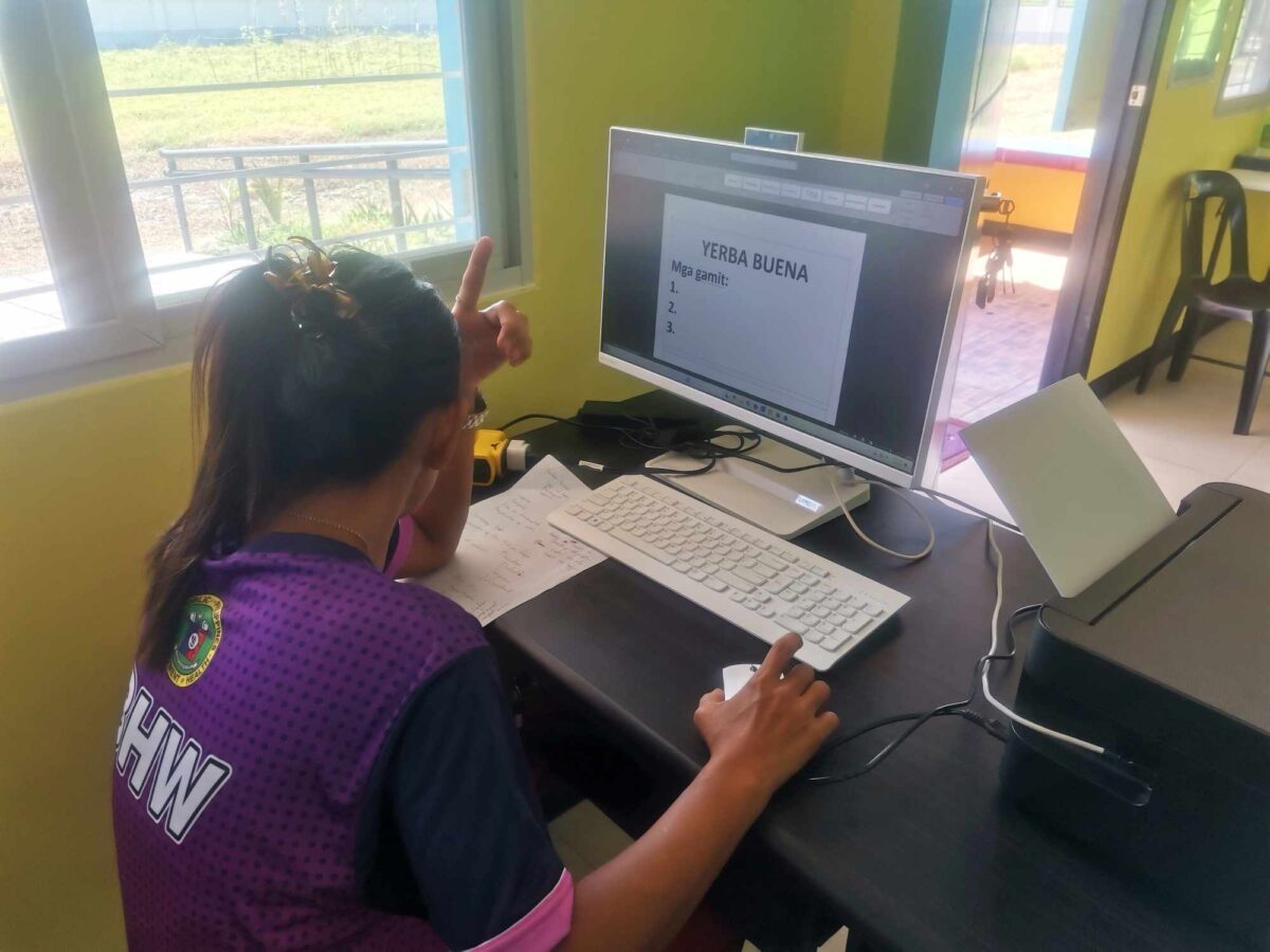 A Barangay Health Worker (BHW) creating a visual aid about a herbal medicine for their health promotion sessions in Barangay Maasin, Pura, Tarlac