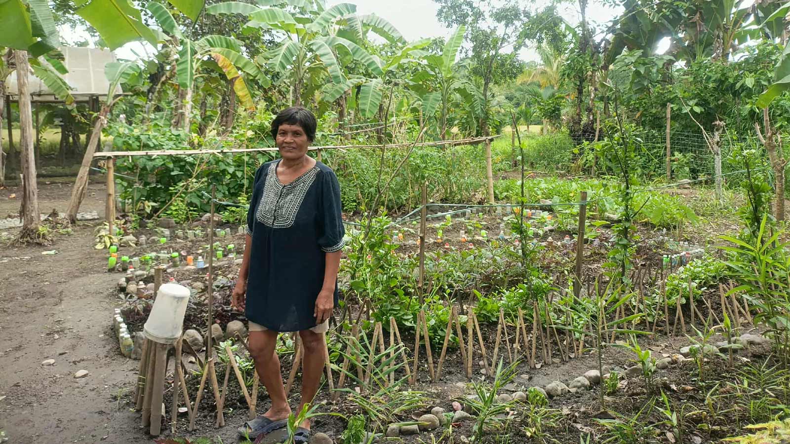 A woman standing with her home garden as her background