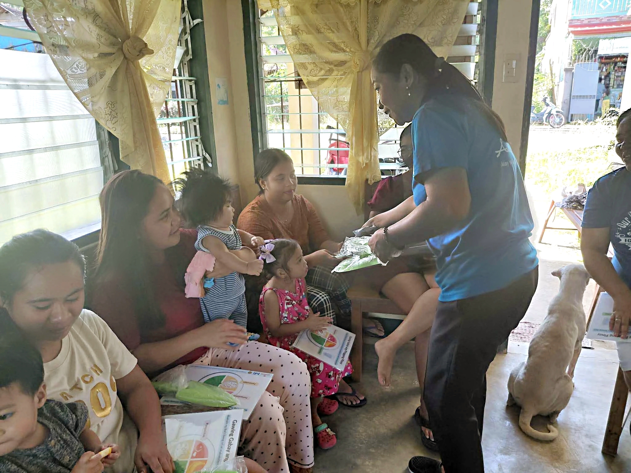 HFI Community Mobilizer, Ms. Joan Malibago, distributes IEC materials on the Healthy Filipino Plate, along with seeds and garden trowels, to beneficiaries in Barangay San Roque to support home gardening and promote healthy eating practices